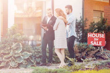 Ev satın alma işlemi sırasında kadın ve erkek danışmanla konuşuyor.