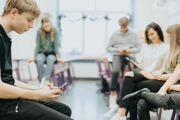 Tonårspojken Svarta Kläder Sitter Skolbänken Och Leker Med Sin Mobiltelefon — Stockfoto