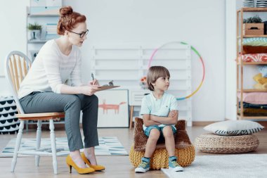 Terapi sırasında otistik çocuğun davranışlarını analiz eden psikolog.