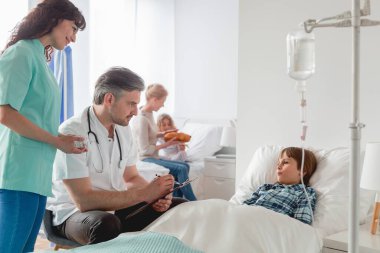 Serum takmış bir kızla ilgilenen bir çocuk doktoru ve hemşire.