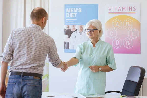 Older dietician greeting new client in the office