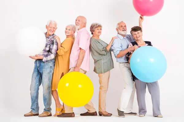 Six Amis Seniors Avec Grands Ballons Colorés Sourit Intérieur Blanc Photos De Stock Libres De Droits