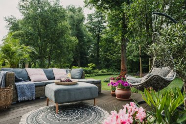 Classy furniture on wooden terrace in green beautiful garden clipart