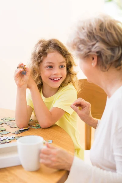 幸せなかわいい子供置くパズルと一緒に彼の祖母 — ストック写真
