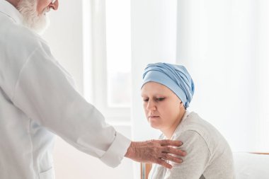 Yaşlı bir doktor, genç bir hastayla üzücü teşhisi paylaşıyor.