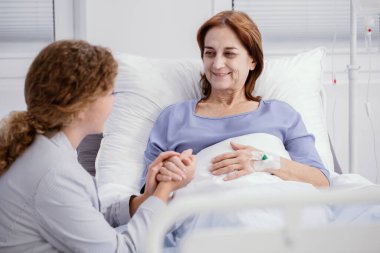 Gülümseyen yaşlı kadın ve bakım evinde elini tutan hemşire.