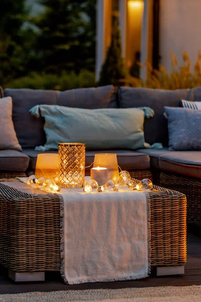 Warme Sommernacht Garten Mit Trendigen Möbeln Lichtern Laternen Und Kerzen lizenzfreie Stockbilder