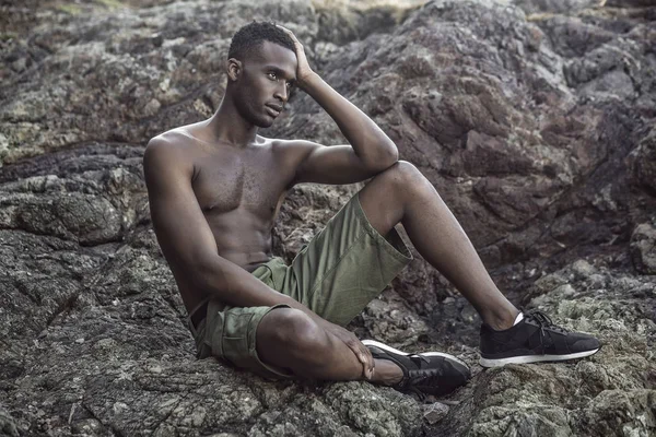 Preto cara senta no o rochoso costa — Fotografia de Stock