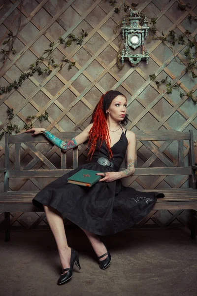 Bankta içinbeklediğini dövmeli kız kırmızı dreadlocks ile