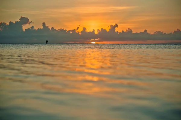 Pôr do sol e siluet de pescador muito longe — Fotografia de Stock