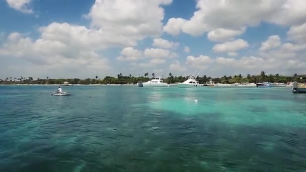 배가 출발하는 것을 보면, 해변에 흰 배, 청록색 바다와 구름이 보인다. bayahibe, 도미니카 공화국, 2015 년 — 비디오