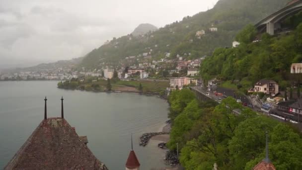 Vue de la plate-forme supérieure du château de Chillon au pont et à la route, déplaçant voitures et bâtiments, sur les rives du lac Léman près de Montreux, Suisse, mai 2019 — Video