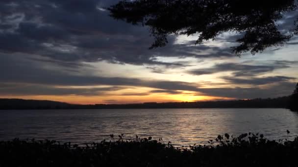 Bela paisagem de nuvens e pôr do sol rompendo as nuvens sobre o rio . — Vídeo de Stock