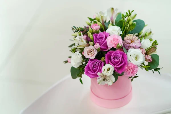 Açık gri arka planda pembe bir tencerede parlak taze çiçekler.