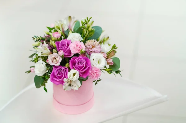 Açık gri arka planda pembe bir tencerede parlak taze çiçekler.