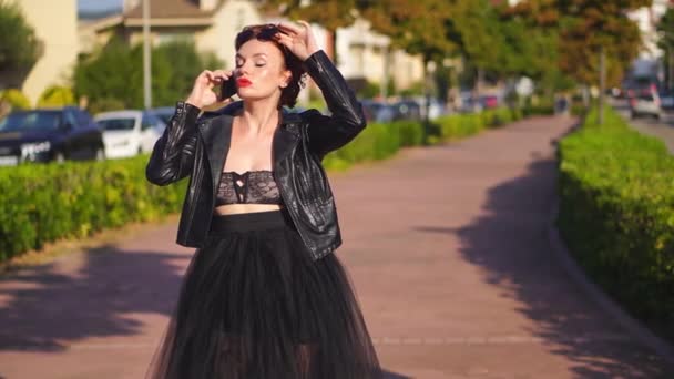 Schöne rothaarige Frau in schwarzer Lederjacke telefoniert — Stockvideo