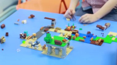 İki çocuk inşaatçıyla oynar, bir şehir inşa eder.