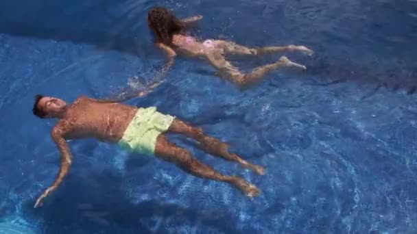 Una pareja feliz, chico y chica nadan lentamente en la piscina en el techo — Vídeo de stock