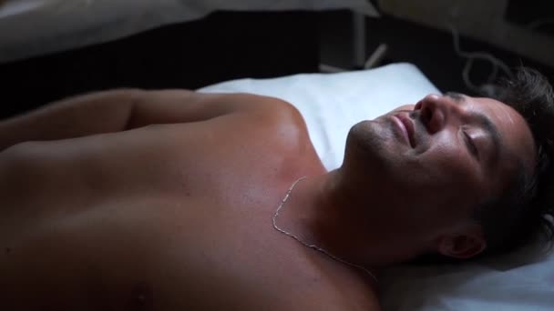 Homme se couche les yeux fermés sur une table de massage — Video