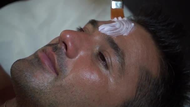 Esiste una procedura per applicare una maschera nutriente con un pennello sul viso per un giovane — Video Stock