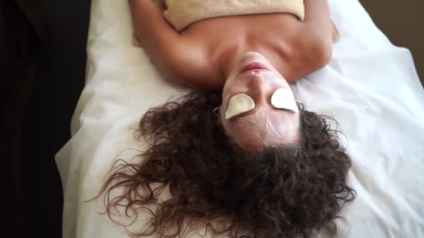 Linda mujer con los ojos cerrados y almohadillas de algodón blanco, toma un tratamiento facial — Vídeo de stock