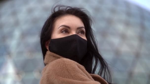 Clouse omhoog portret van een vrouw in een zwart masker en beige jas — Stockvideo