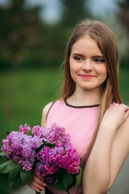 Sevimli kız pembe bluz ve siyah etek güzel çiçekli ağaçlar arka plan üzerinde fotoğrafçılar için poz veriyor. Bahar. Sakura.