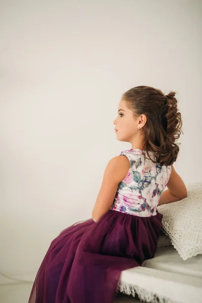 Mooi meisje in een paarse jurk en bloem blouse poseren voor een fotograaf. Fotosessie voor het magazine. — Stockfoto