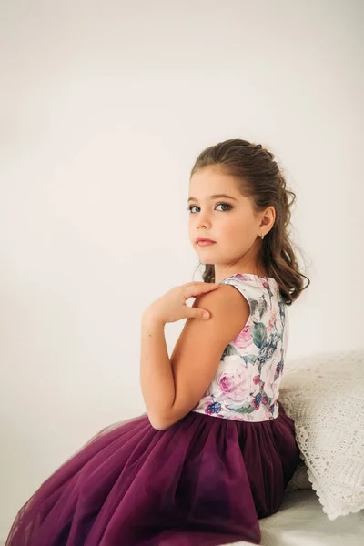 Όμορφο κορίτσι σε ένα μωβ φόρεμα και λουλουδένια Mπλούζα ποζάρουν για έναν φωτογράφο. Photosession για το περιοδικό. — Φωτογραφία Αρχείου
