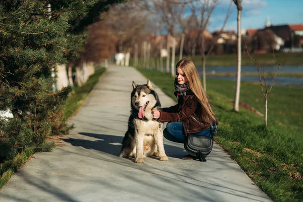 Une fille marche avec un chien le long du remblai. Magnifique chien Husky. La rivière. Printemps . — Photo