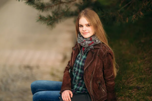 Een mooi meisje is een wandeling langs de kade. Blond haar en bruine jas. Lente. — Stockfoto