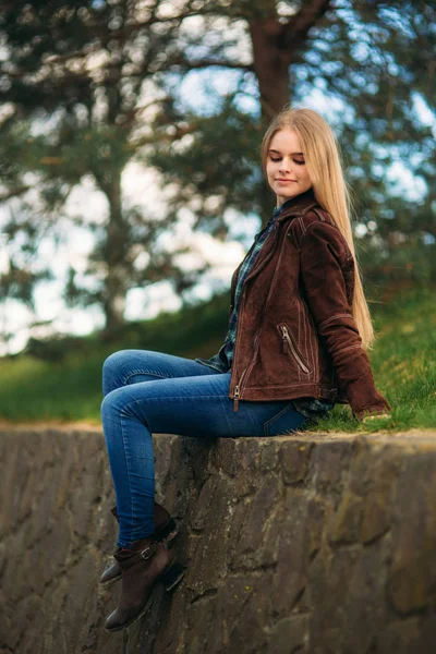 Een mooi meisje is een wandeling langs de kade. Blond haar en bruine jas. Lente. — Stockfoto