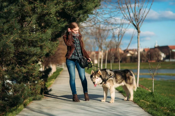 Ein Mädchen geht mit einem Hund die Böschung entlang. schöner Husky-Hund. der Fluss. Frühling. — Stockfoto