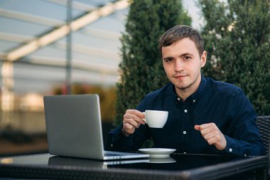 Bir kafede dizüstü bilgisayarda çalışan genç bir programcı