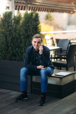 Genç bir adamın cep telefonundan konuşuyor. İş