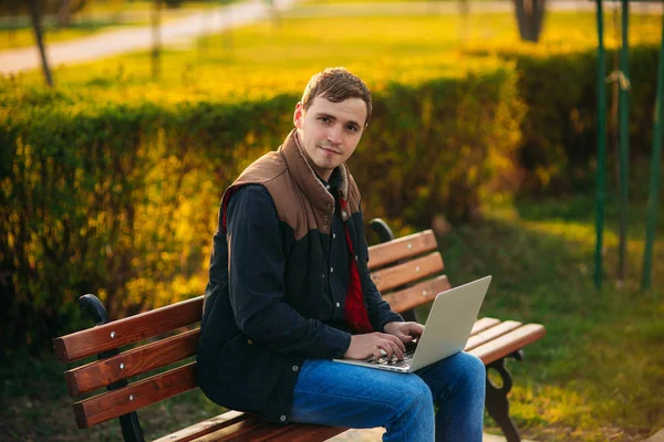 De jonge manager werken op een laptop in het park. Lunchpauze. — Stockfoto