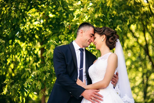 Schönes Paar, das am Hochzeitstag im Park spazieren geht. sonniges Wetter. — Stockfoto