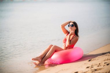 Seksi kız sahilde pembe bir mayo içinde. Yaz. Güneşli havalarda.