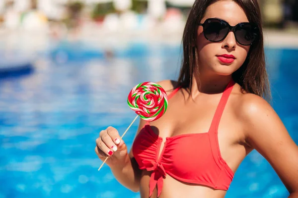 Una hermosa chica en un traje de baño rosa tomando el sol junto a la piscina. Clima soleado. Verano . —  Fotos de Stock