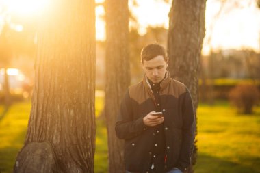 Koyu mavi gömlekli bir parkta genç bir adam. Bahar.
