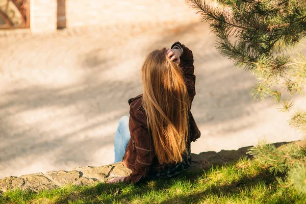 Een mooi meisje is een wandeling langs de kade. Blond haar en bruine jas. Lente. — Stockfoto