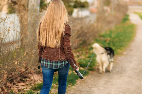 Une belle fille marche le long du remblai. Cheveux blonds et veste brune. Printemps . — Photo