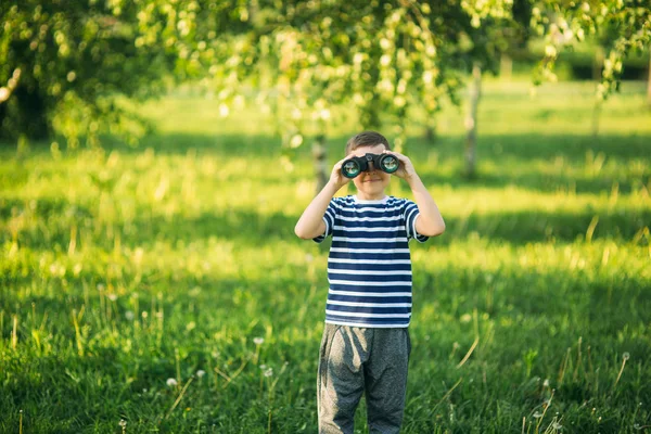 Kleiner Junge im gestreiften T-Shirt blickt durch ein Fernglas. Frühling, sonniges Wetter.. — Stockfoto