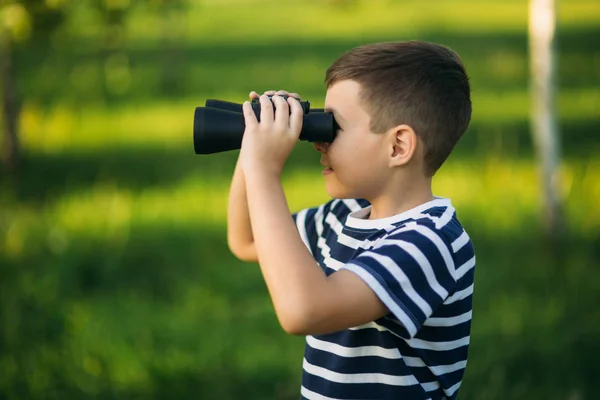 Niño con una camiseta a rayas mira a través de los prismáticos. . — Foto de Stock