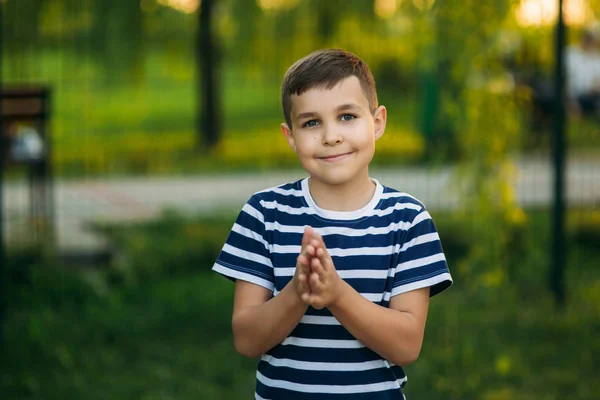 Un bambino con una maglietta a righe sorride e si rallegra. Primavera, tempo soleggiato . — Foto Stock