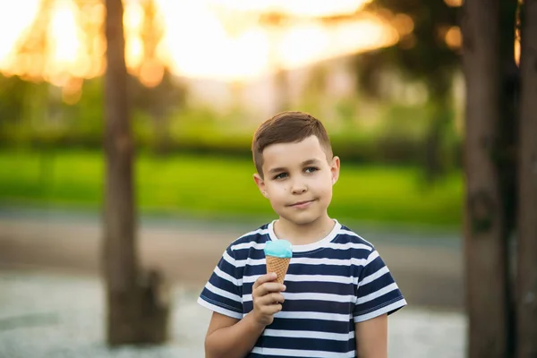 Egy kis fiú a csíkos póló kék fagylalt eszik. Tavasz, napsütés. — Stock Fotó