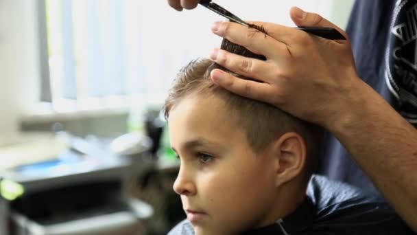 Bambino ottenere taglio di capelli da barbiere mentre seduto in sedia a barbiere . — Video Stock