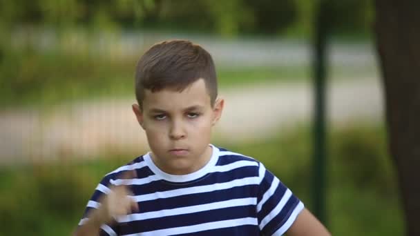 Маленький мальчик в полосатой футболке улыбается и ликует. . — стоковое видео