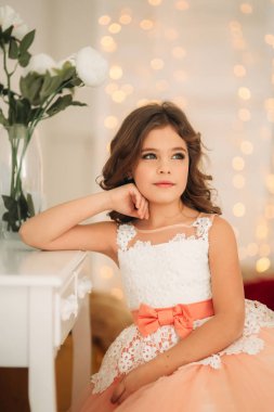 Güzel kız bir şeftali renkli elbiseli kahverengi saçlı. Bir fotoğrafçı için pozlar