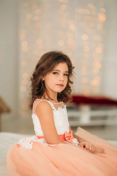 Menina bonita pequena com cabelo castanho em um vestido de cor de pêssego. Poses para um fotógrafo — Fotografia de Stock